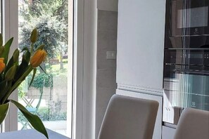 A modern kitchen with a built-in oven and a window with a view of greenery.