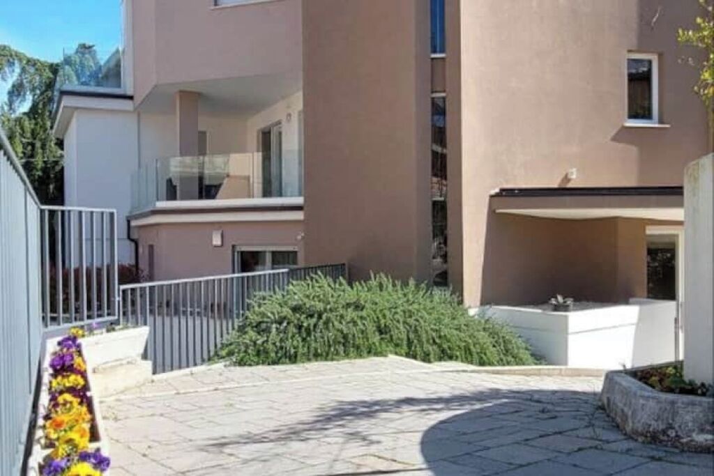 Ein modernes Gebäude mit Flachdach, einem Balkon und einem gepflasterten Innenhof.