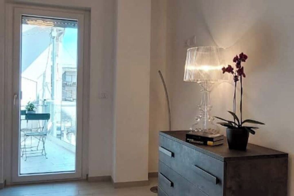Een kamer met een schuifdeur naar een buitenruimte, een dressoir met een lamp en een potplant.