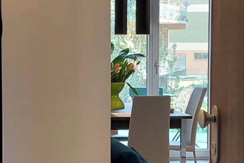 Ein Zimmer mit Esstisch, Stühlen, einer Topfpflanze und Blick ins Freie.
