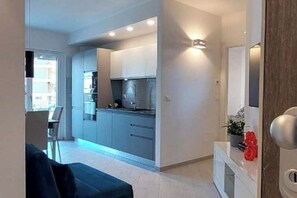 A modern kitchen with built-in appliances and a dining area with a sofa.