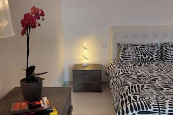 A bedroom with a zebra-patterned bedspread, a bedside lamp, and a potted plant.