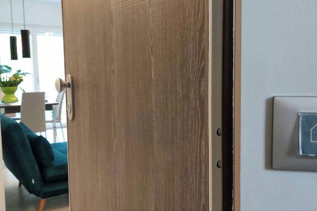 Eine Holztür mit Griff, Lichtschalter und einer Wandleuchte.
