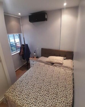 A bedroom with a bed, a desk, a chair, a window, and a wall-mounted air conditioner. - Modern Copacabana - Ipanema in the best location in Rio de Janeiro. (Rio de Janeiro)
