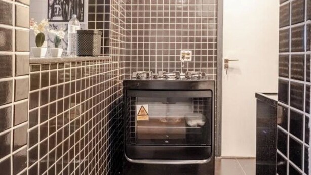 Une cuisine avec un mur recouvert de carreaux, une cuisinière et un évier.