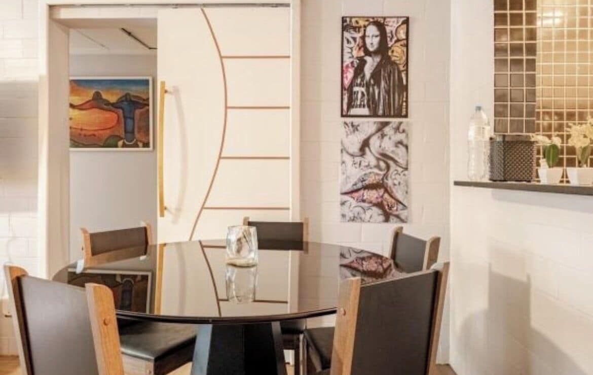 Un comedor con una mesa redonda, sillas y obras de arte en las paredes.