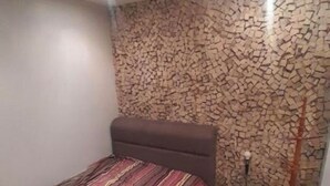 Une chambre à coucher avec un lit, un mur décoré d’un motif imitant la pierre et un plancher en bois.