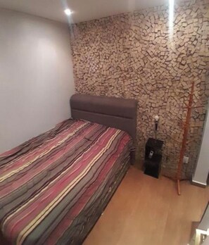 Ein Schlafzimmer mit einem Bett, einer Wand mit Steinmuster und einem Holzboden.