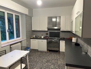 A compact kitchen with white cabinets, a black countertop, and a window with a view of trees. - Spacious Villa with Private Park in Verucchio (Emilia-Romagna)