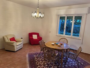 A dining area with a round table, chairs, a red armchair, a beige armchair, a patterned rug, and a chandelier. - Spacious Villa with Private Park in Verucchio (Emilia-Romagna)