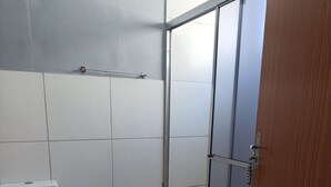 A bathroom with a toilet, a shower with a glass door, and a wooden door.