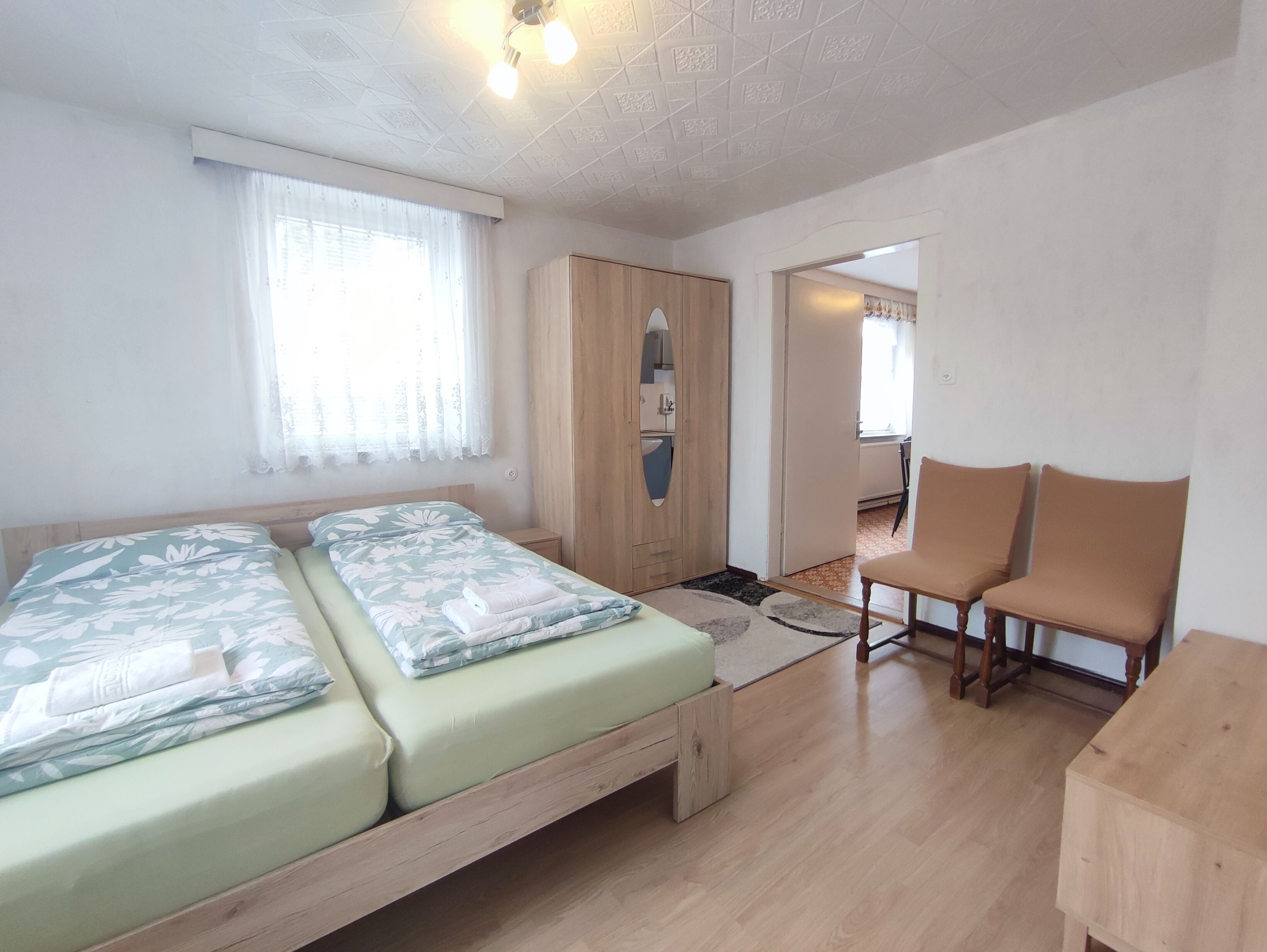 Une chambre avec deux lits, une armoire, un bureau et une chaise.