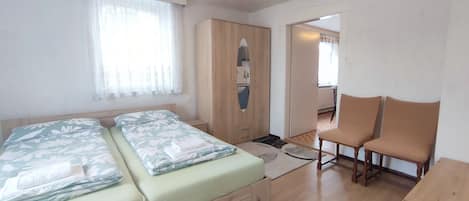 A bedroom with two beds, a wardrobe, a desk, and a chair.