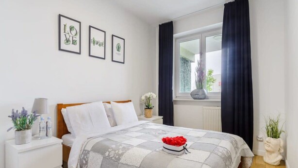 Ein Schlafzimmer mit einem Bett, einem Nachttisch, einem Fenster mit Vorhängen und drei gerahmten Bildern an der Wand.