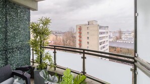 Ein Balkon mit Blick auf einen Fluss und Gebäude, eine Topfpflanze und ein Stuhl.