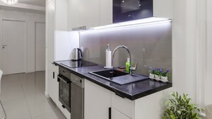 Eine moderne Küche mit schwarzem Arbeitsplatz, Edelstahlgeräten und einem eingebauten Backofen.