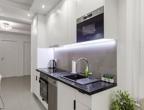 A modern kitchen with a black countertop, stainless steel appliances, and a built-in oven. - Spacious Central Warsaw Apartment (Warsaw)