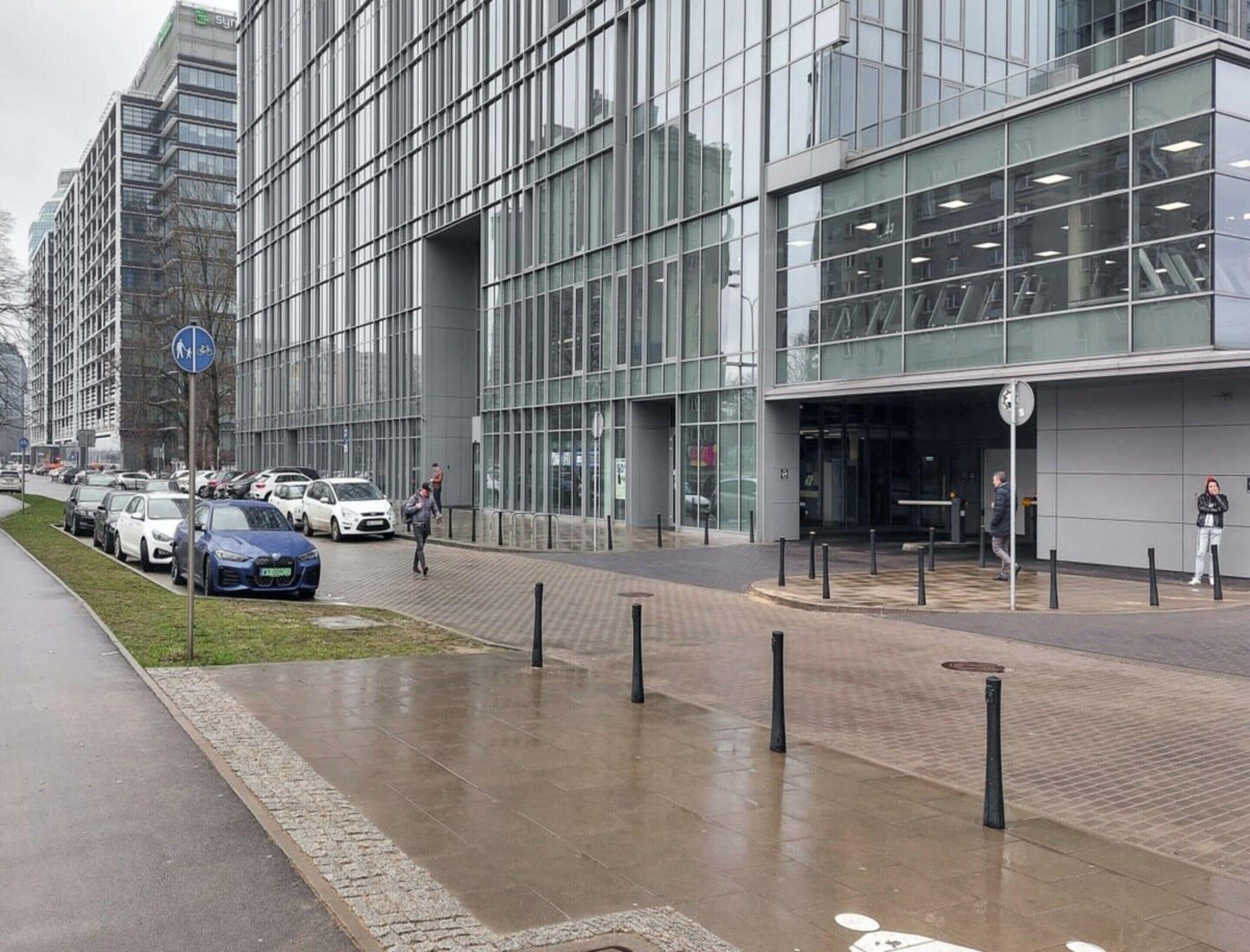 A modern building with large windows and a paved sidewalk.