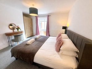 Ein Schlafzimmer mit einem Bett, einem Schreibtisch, einem Spiegel und einem Fenster mit Vorhängen.
