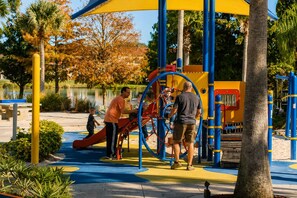 A playground with a slide and climbing structures, surrounded by trees and a body of water. - CASA VERDE RESORT PROPERTY 20 MINS to DISNEY (Kissimmee)