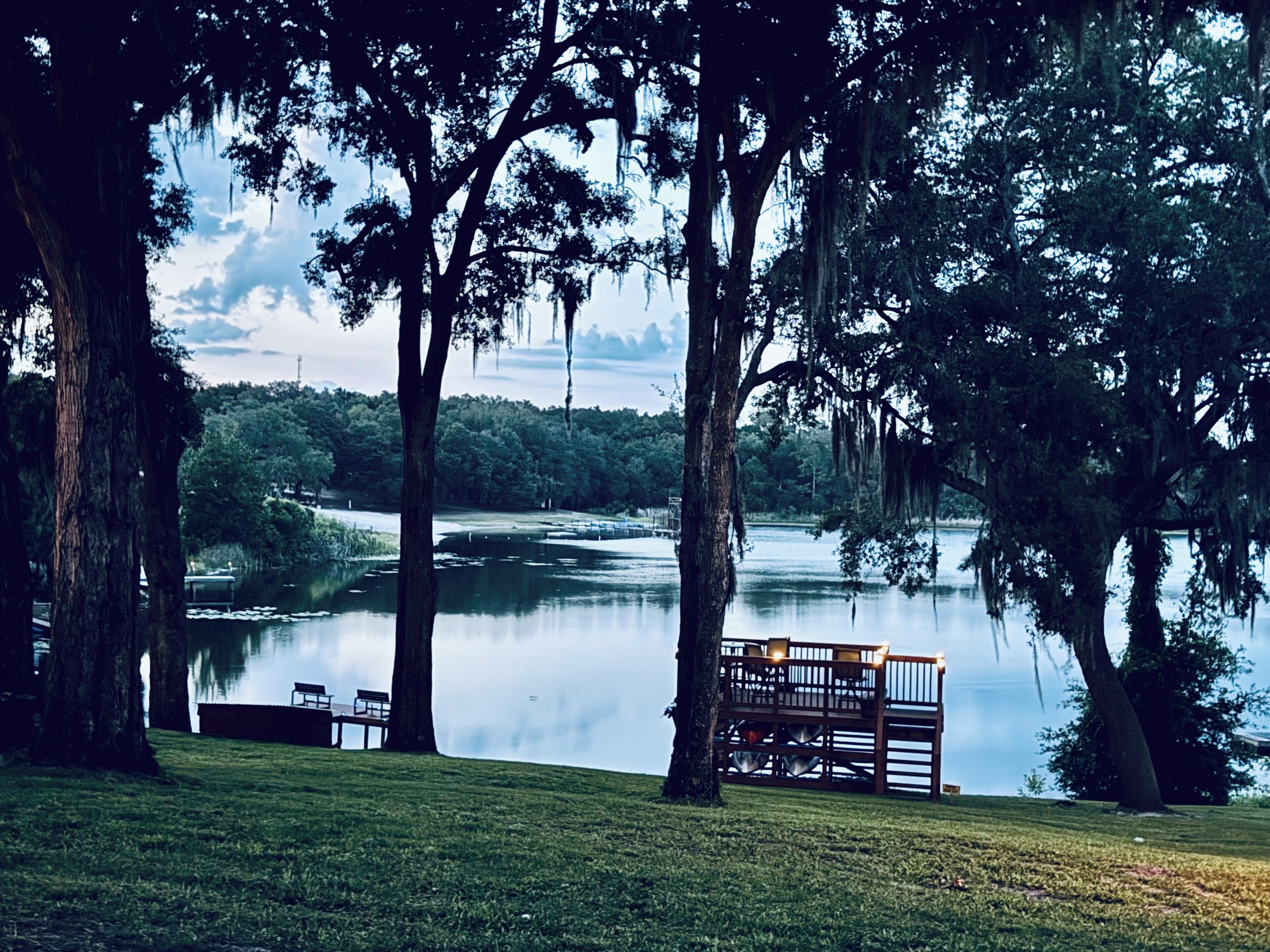 A lakeside view with a wooden deck and chairs overlooking the water.