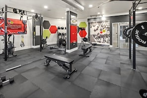 A gym with various exercise equipment, including a bench, weight plates, and a wall clock. - Presidential 1BR Suite-Adjustable Bed & Seating-Resort Pool, Gym & Clubhouse (Charlotte)