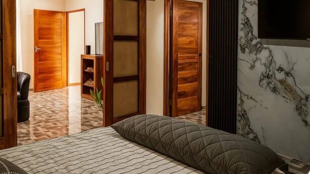 Une chambre à coucher avec un lit, un téléviseur fixé au mur et une armoire en bois.