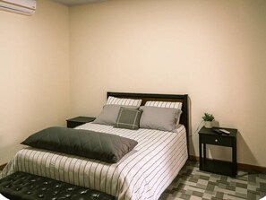 A bedroom with a bed, a nightstand, a small table, and an air conditioning unit. - Cozy 1-bedroom house La Fortuna with AC volcano view, swimming pool and Jacuzzi (La Fortuna)