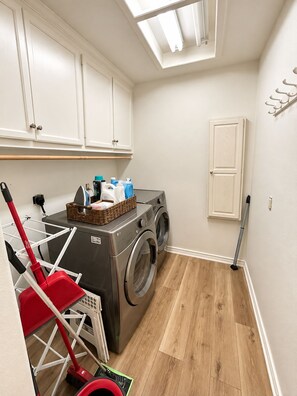 A laundry room with a washing machine, a drying rack, and a broom. - 3-bedroom near Texas A&M Campus! (College Station)