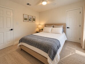 Ein Schlafzimmer mit einem Bett, einem Nachttisch, einer Lampe und gerahmten Bildern an der Wand.
