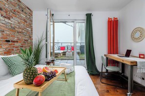 A cozy living space with a brick wall, a sofa, a dining area with a table, and a view through a glass door. - Warsaw Flat Near Praga Park (Warsaw)