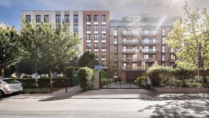 Ein mehrstöckiges Wohngebäude mit modernem Design, mit Balkonen und einem verschlossenen Eingang.