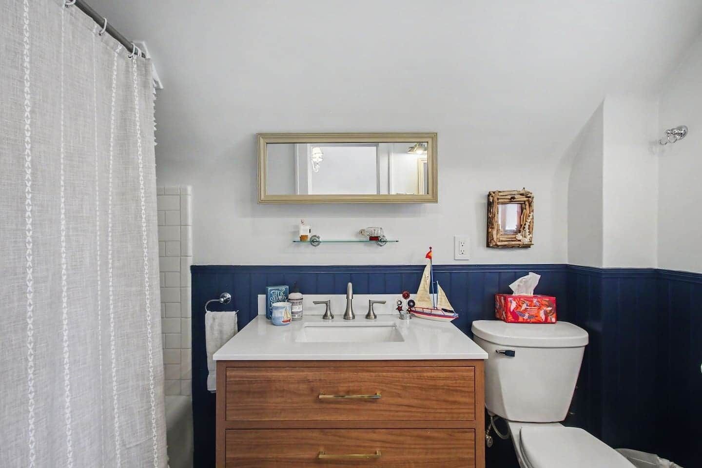 A bathroom with a white sink, a mirror, a toilet, and a shower curtain.