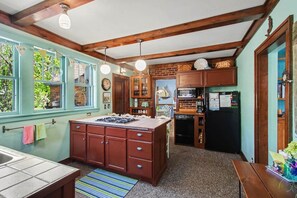 A kitchen with wooden cabinets, a central island, and a dining area. - Unsalted Tides-Walk to Beach + Town + Dog-Friendly (South Haven)