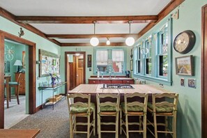 A kitchen with a central island, wooden chairs, and a dining table. - Unsalted Tides-Walk to Beach + Town + Dog-Friendly (South Haven)