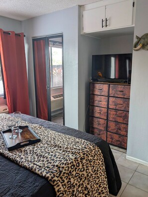 A bedroom with a bed, a television on a cabinet, and a window with curtains. - Forbidden Safari - Your Dockside Paradise Lakes Stay (Lutz)