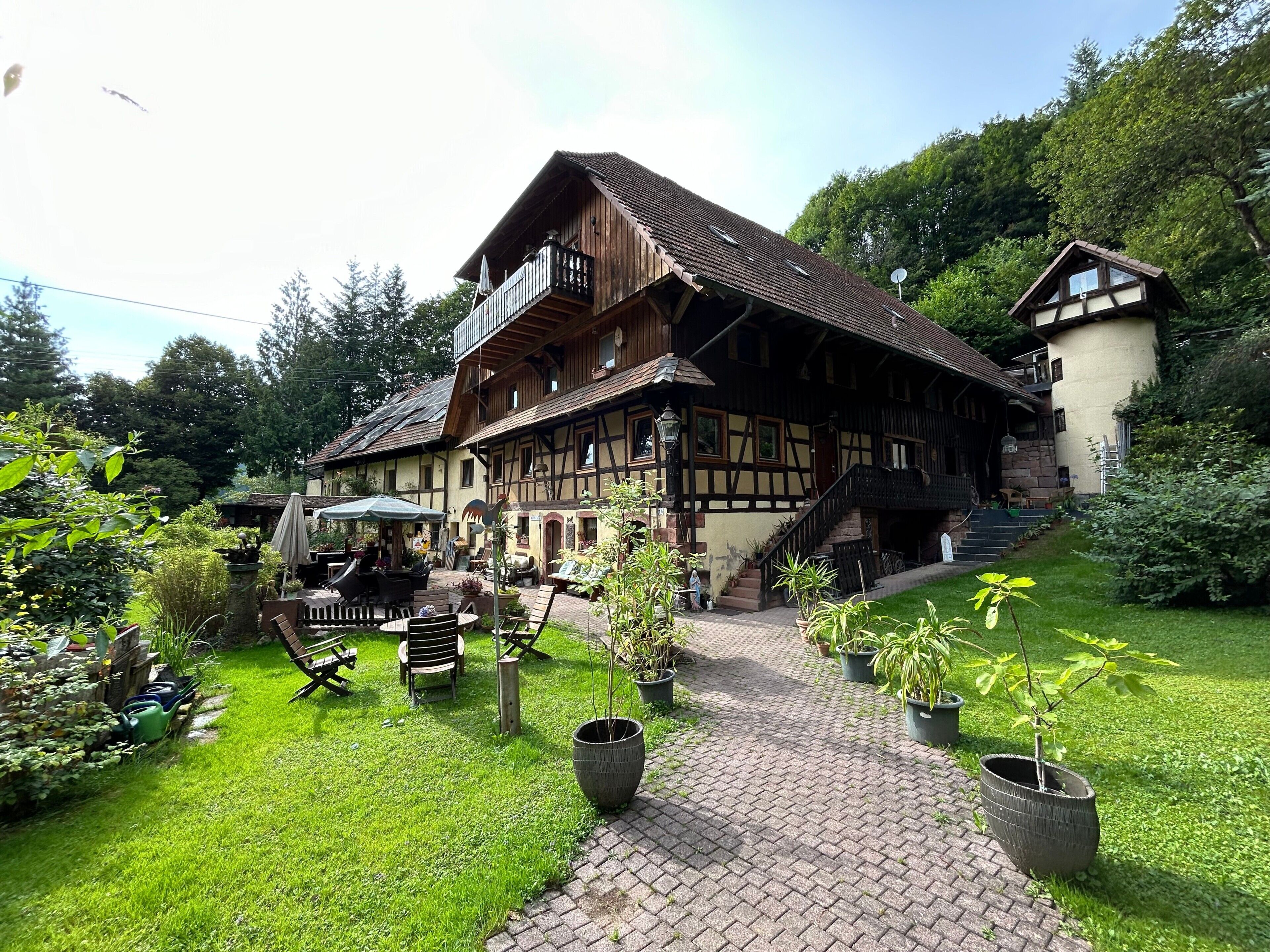 Ein traditionelles Fachwerkhäus mit Balkon, einem gepflasterten Weg und Blumentöpfen.