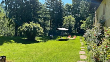 Een verzorgde tuin met gazon, een pad van stenen en een zithoek met een tafel en stoelen.
