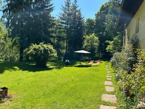Een verzorgde tuin met gazon, een pad van stenen en een zithoek met een tafel en stoelen.