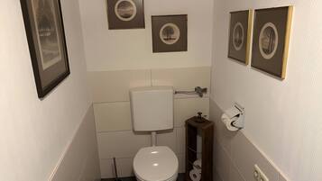 Ein kleines, modernes Badezimmer mit Toilette, Bidet und Toilettenpapierhalter.