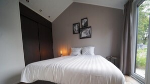 A modern bedroom with a large bed, a dark wardrobe, and a bedside table. - Chalet Near Efteling Theme Park (Kaatsheuvel)