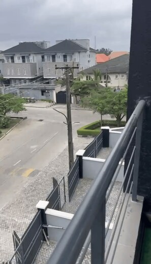 Una calle residencial con casas, cielo despejado y una acera.