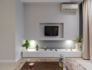 A modern living room with a mounted TV, white console, decorative items, and a coffee table. - City Apartment With Balcony (Warsaw)