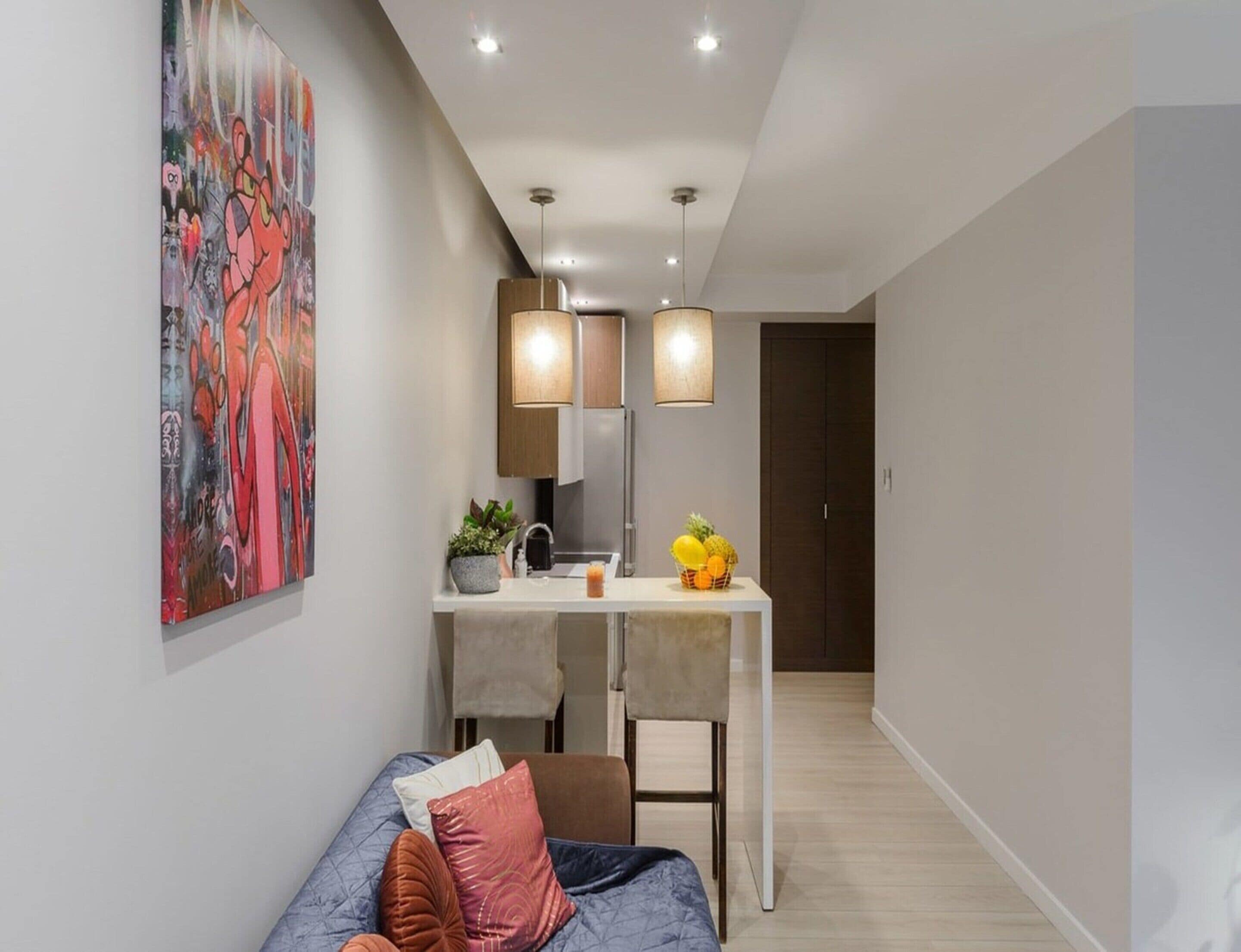 Un salon moderne comprenant un canapé, un coin repas avec une table et des chaises, et un espace cuisine avec un réfrigérateur.