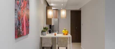 Una sala moderna con un sofá, un comedor con mesa y sillas, y una cocina con refrigerador.