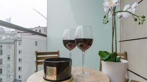 Pyöreä puinen pöytä, jonka päällä on kaksi viinilasia ja kynttilänjalka, ja pöytä on sijoitettu parvekkeelle, jolta avautuu näkymä kaupungin ylle.