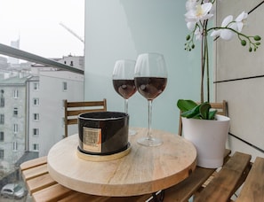 A round wooden table with two wine glasses and a candle holder on a balcony overlooking a cityscape. - City Apartment With Balcony (Warsaw)