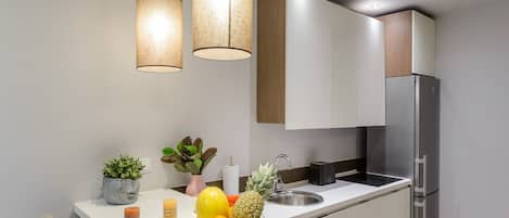 A modern kitchen with a stainless steel refrigerator, white cabinets, and a white countertop.