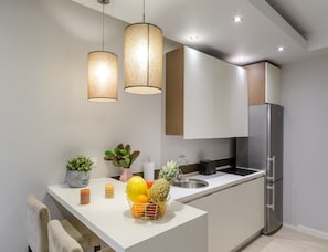 A modern kitchen with a stainless steel refrigerator, white cabinets, and a white countertop. - City Apartment With Balcony (Warsaw)