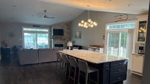 A modern kitchen with a large island, bar stools, and a dining area. - Spacious 4-bedroom, waterfront townhome at Lake Gaston (Henrico)